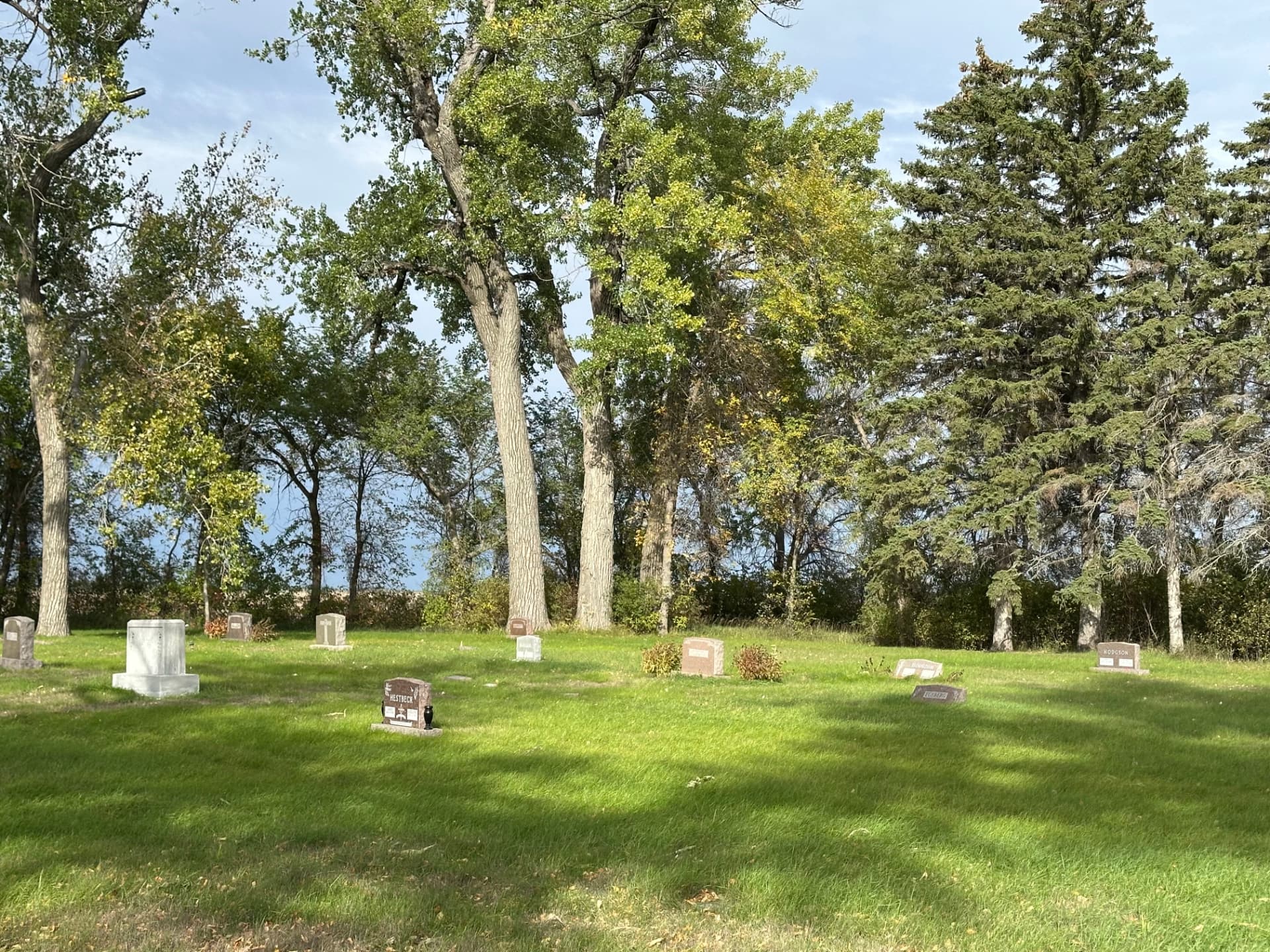 Headstones and green lawns beneath the trees at Argusville Cemetery